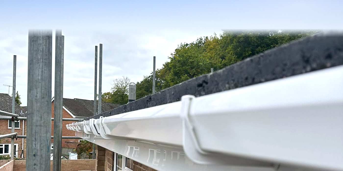 A new white gutter run along the eaves, seen from the scaffold