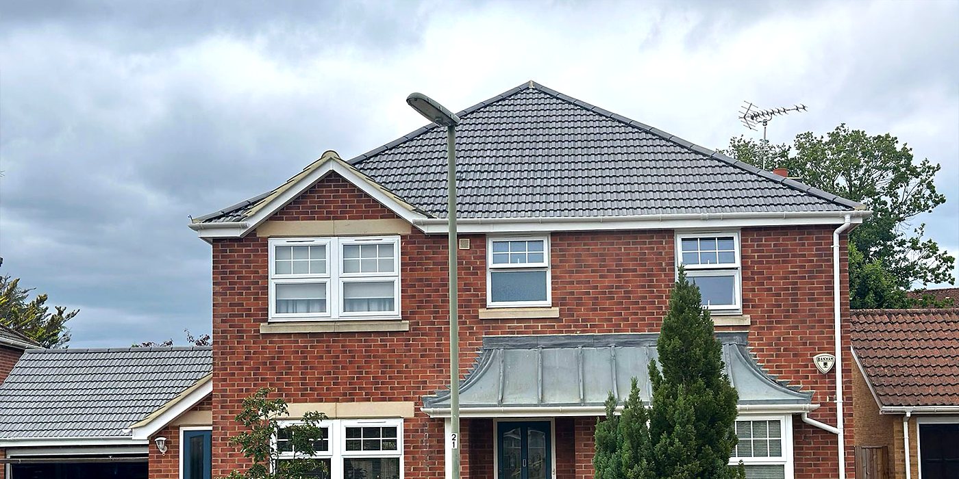 A detached house with a new tiled roof, seen from the kerb
