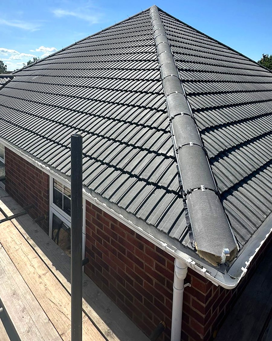 Newly tiled hipped roof seen from the scaffold, ridge and hip tiles bedded in