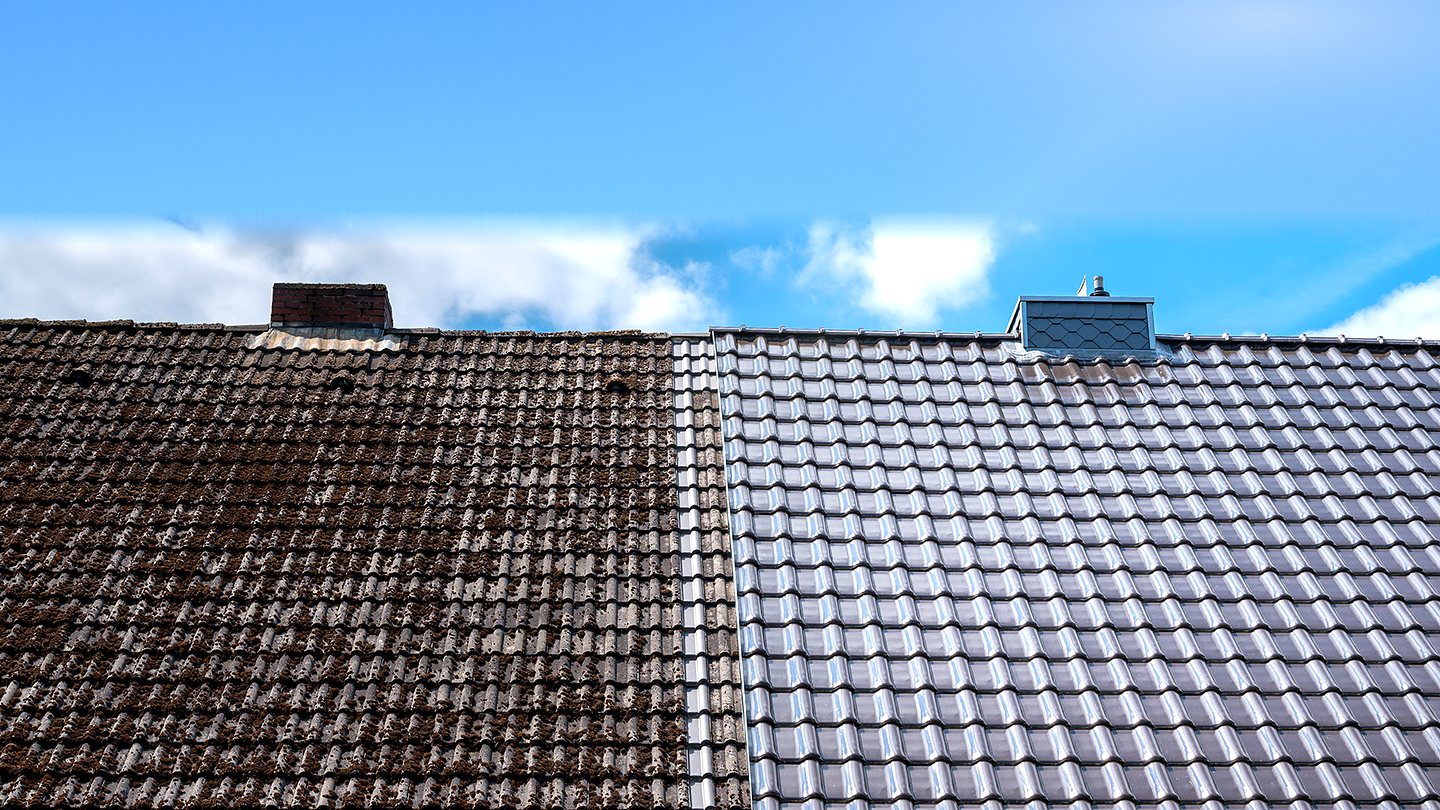 A pitched roof caught halfway through a re-tile: old mossy tiles on one side, new grey tiles on the other