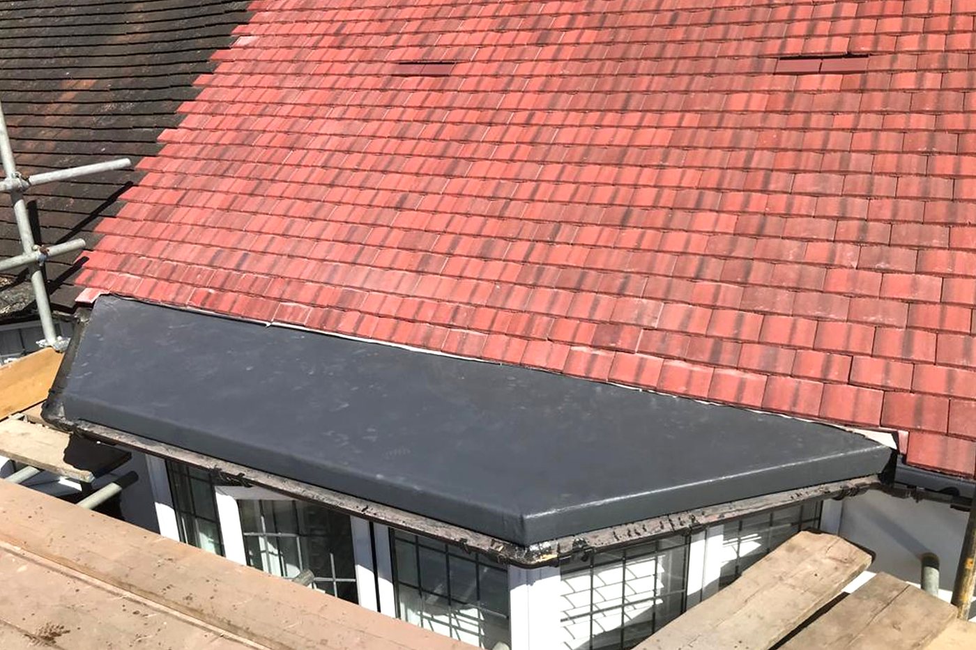 A red plain tile roof next to a flat roof, seen from above