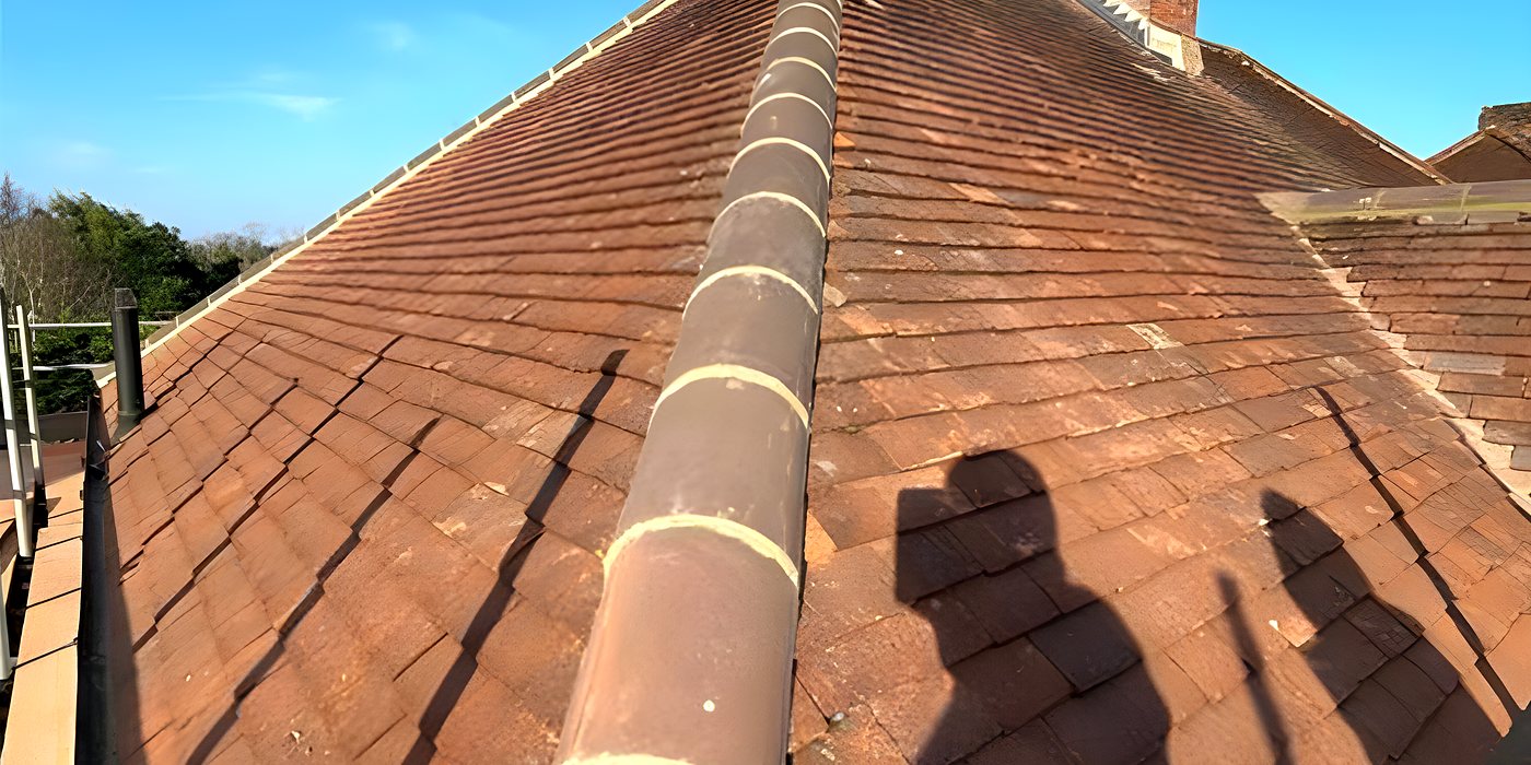Roofing work in Burgess Hill: a clay tiled hipped roof against a blue sky