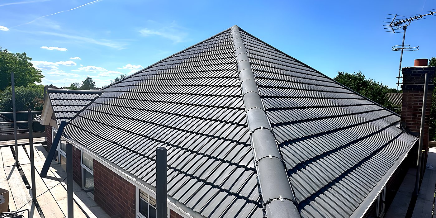 Roofing work in Cobham: a hipped roof in grey concrete tile against a blue sky