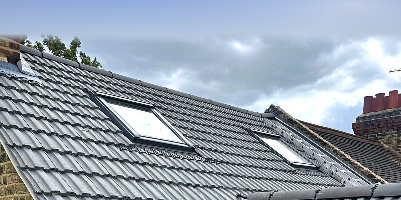Roofing work in Raynes Park: a roof window set into grey tiles